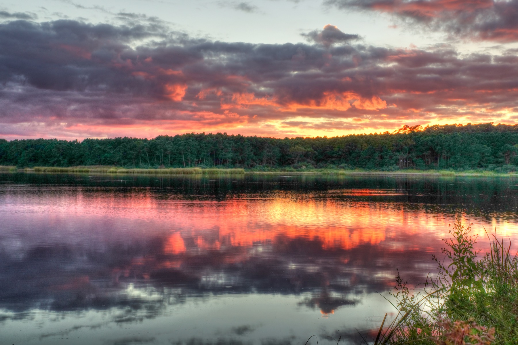 A vivid sunset reflected across the water at Huntington Beach State Park